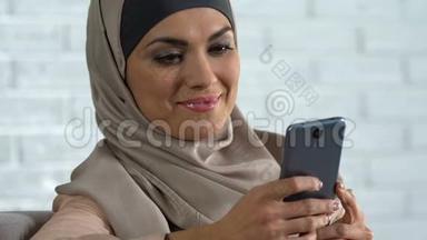 迷人的阿拉伯女人在智能手机上滚动社交网络，现代科技